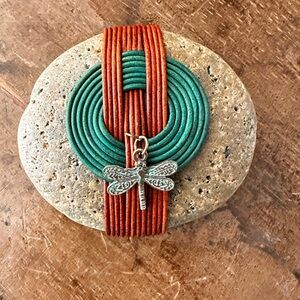 Hand wrapped stone in Teal and Rust with a delicate dragonfly charm.